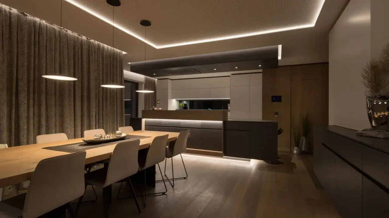 Comedor y cocina modernos con luces domóticas integradas que crean un ambiente acogedor.