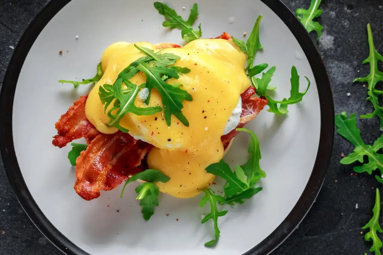 &Auml;gg Benedict med kr&auml;mig hollandaises&aring;s, knaperstekt bacon och ruccola. Ett perfekt hollandaises&aring;s recept f&ouml;r en lyxig brunch.