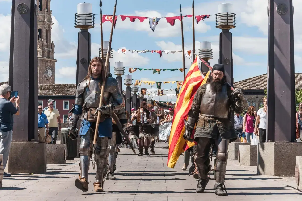 Hombres con armadura desfilan portando lanzas y una bandera, evocando el mercado medieval de las tres culturas.