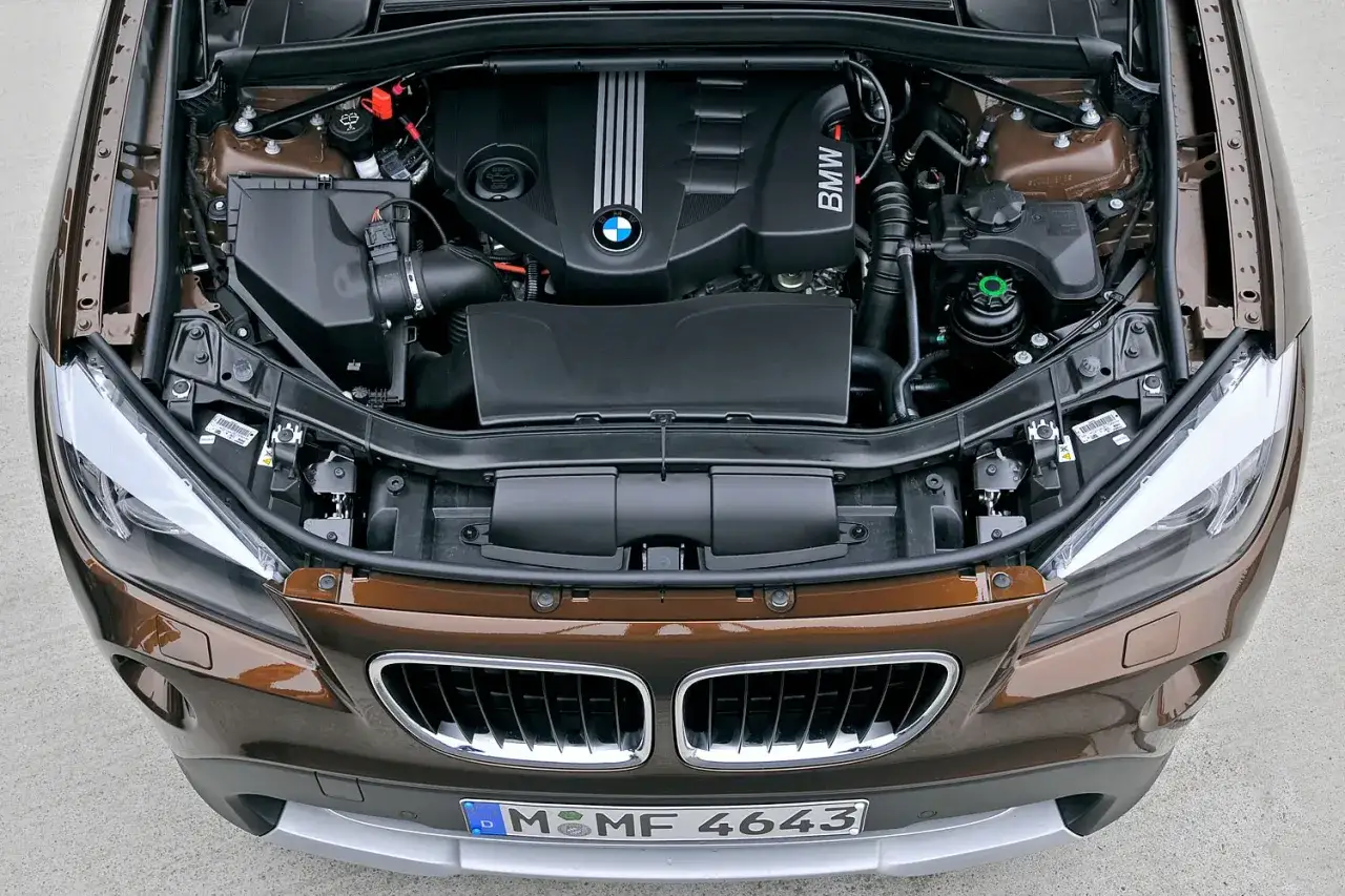 Offener Motorraum eines braunen BMW X1. Welcher Motor ist der beste? Hier sieht man den BMW-Motor.
