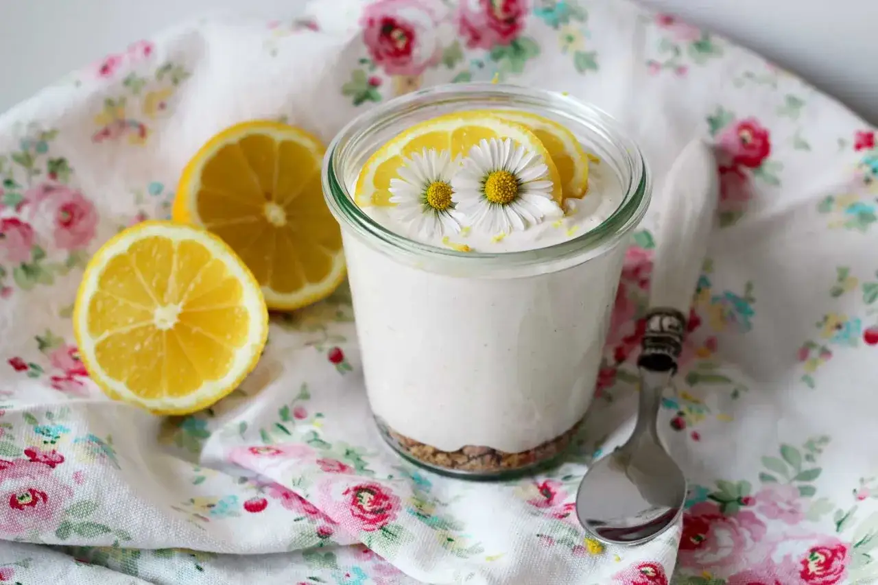 Erfrischendes Dessert im Glas, inspiriert vom lemon curd rezept. Mit Zitronenscheiben und G&auml;nsebl&uuml;mchen dekoriert.