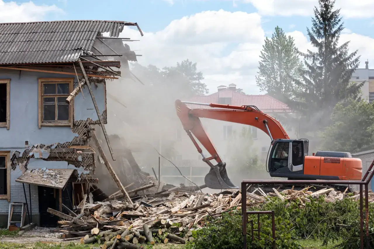 Koparka rozbiórkowa pracuje przy burzeniu budynku. Szukasz informacji o firmy rozbiórkowe cennik?