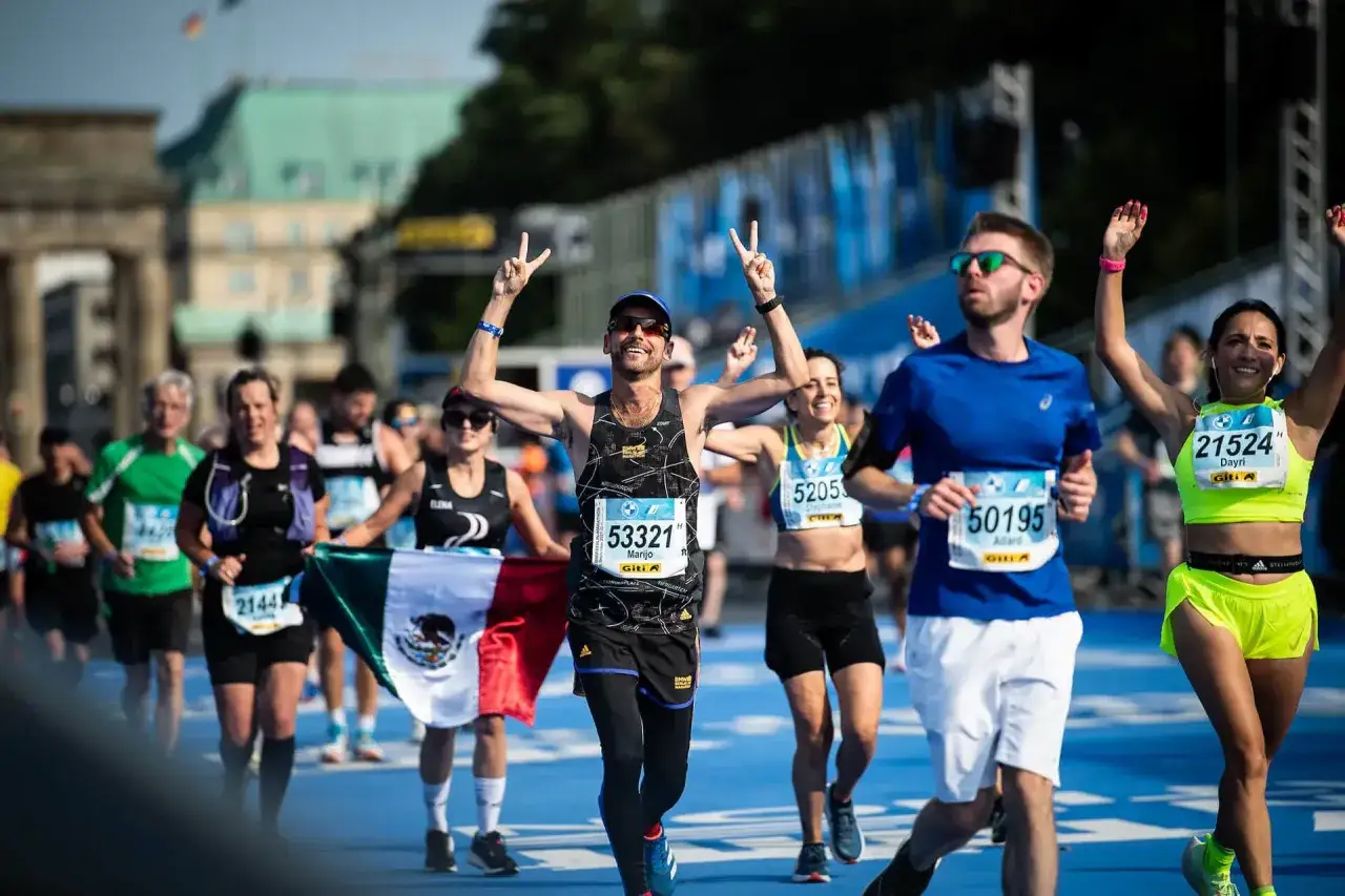 Biegacze świętują na mecie maratonu, jeden z nich z flagą Meksyku. To ich korona maraton&oacute;w świata!