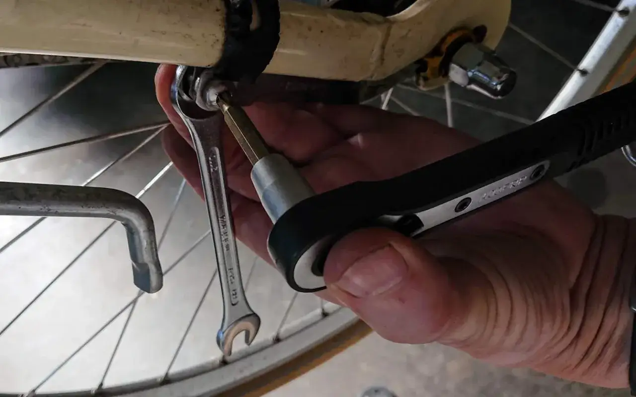 Handen använder verktyg för att laga punktering på cykeln.