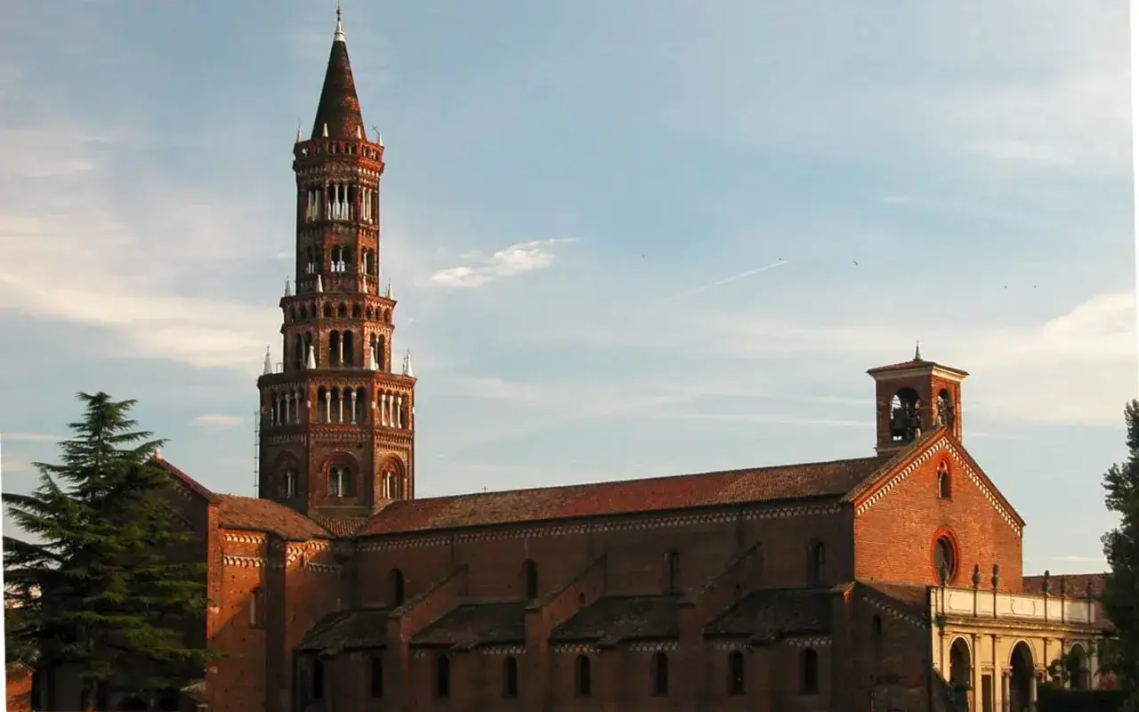 L'imponente torre campanaria della abbazia di Chiaravalle si staglia contro il cielo azzurro, con la sua struttura in mattoni rossi e le arcate gotiche.