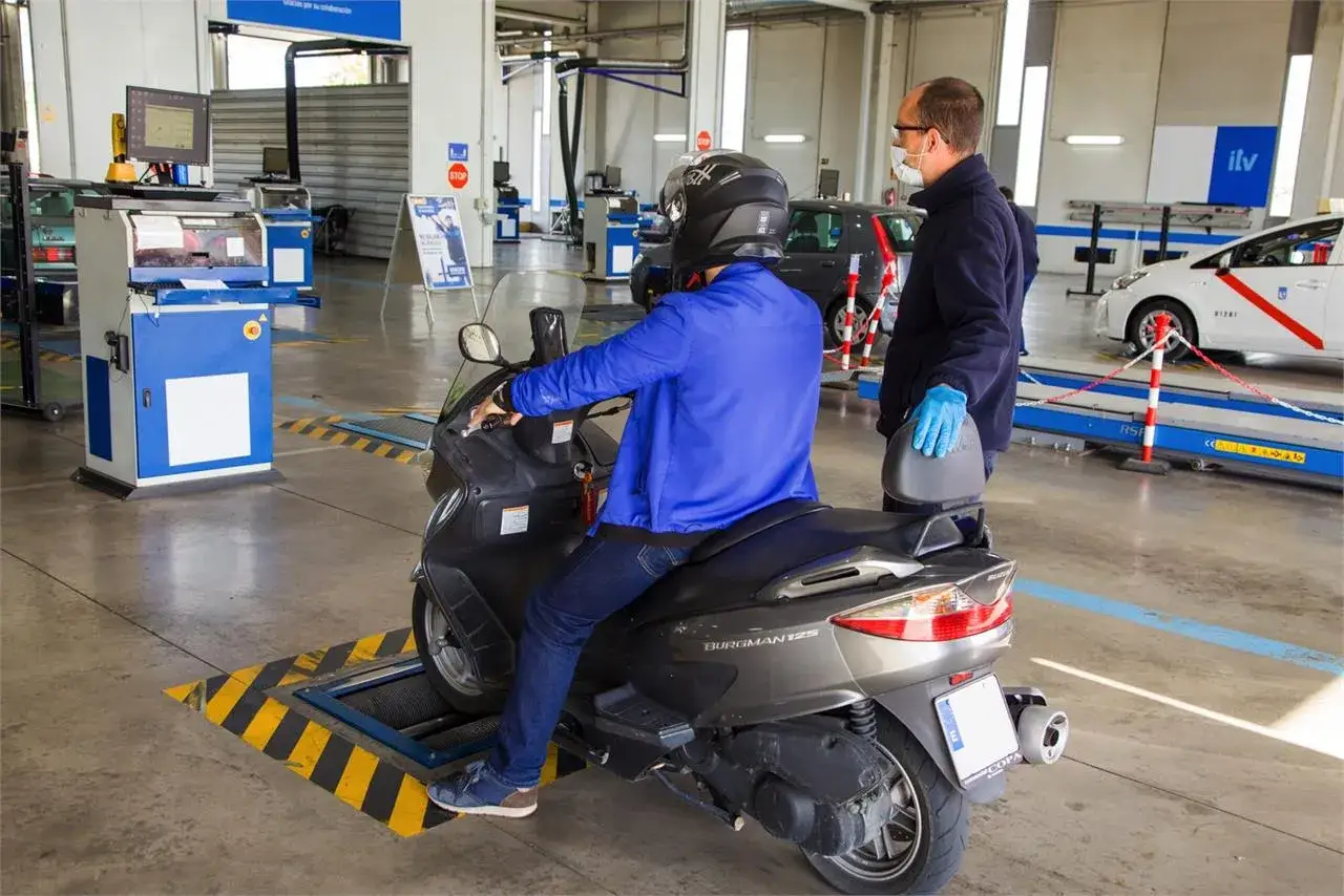 Un hombre en moto pasa la primera ITV. Un t&eacute;cnico con mascarilla supervisa la inspecci&oacute;n en un centro de la ITV.