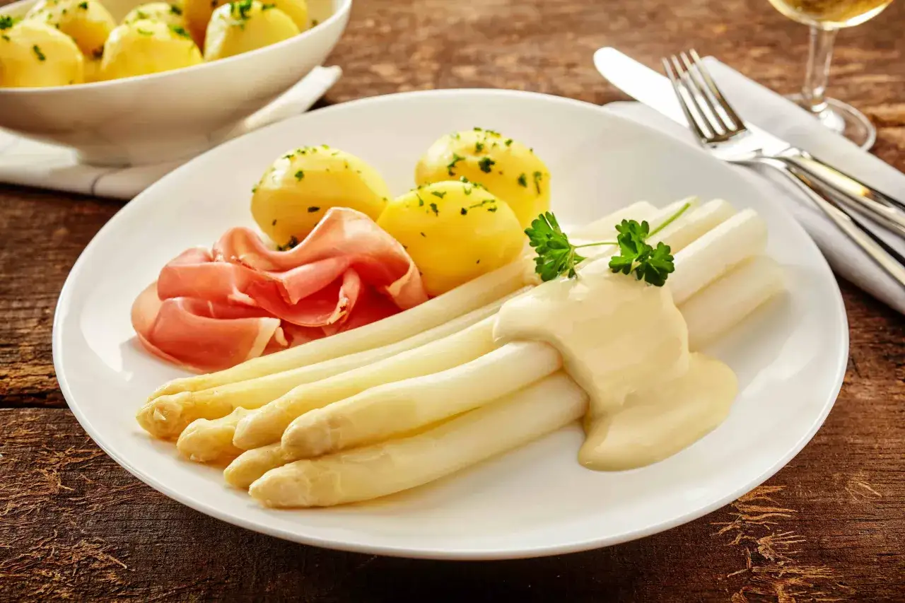 Frischer wei&szlig;er Spargel aus dem Glas mit cremiger Sauce Hollandaise, dazu Pellkartoffeln und Schinken.