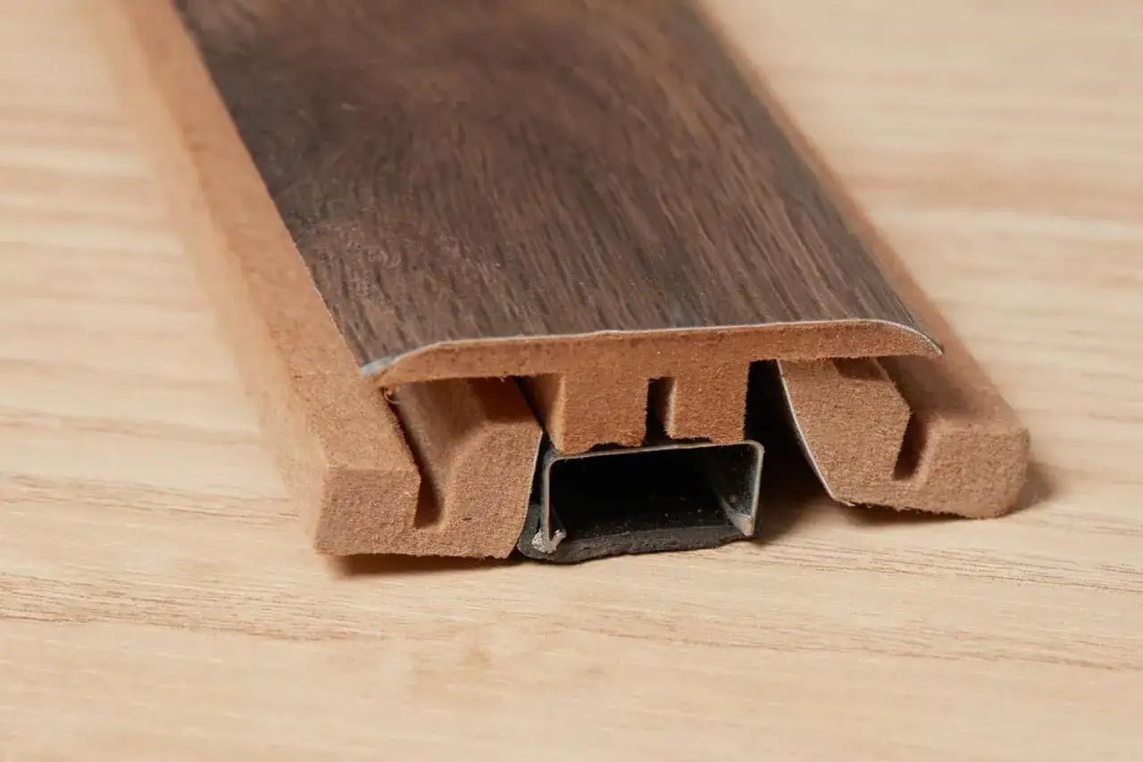 A close-up shows a flooring transition strip, designed for a seamless transition from tile to laminate flooring.