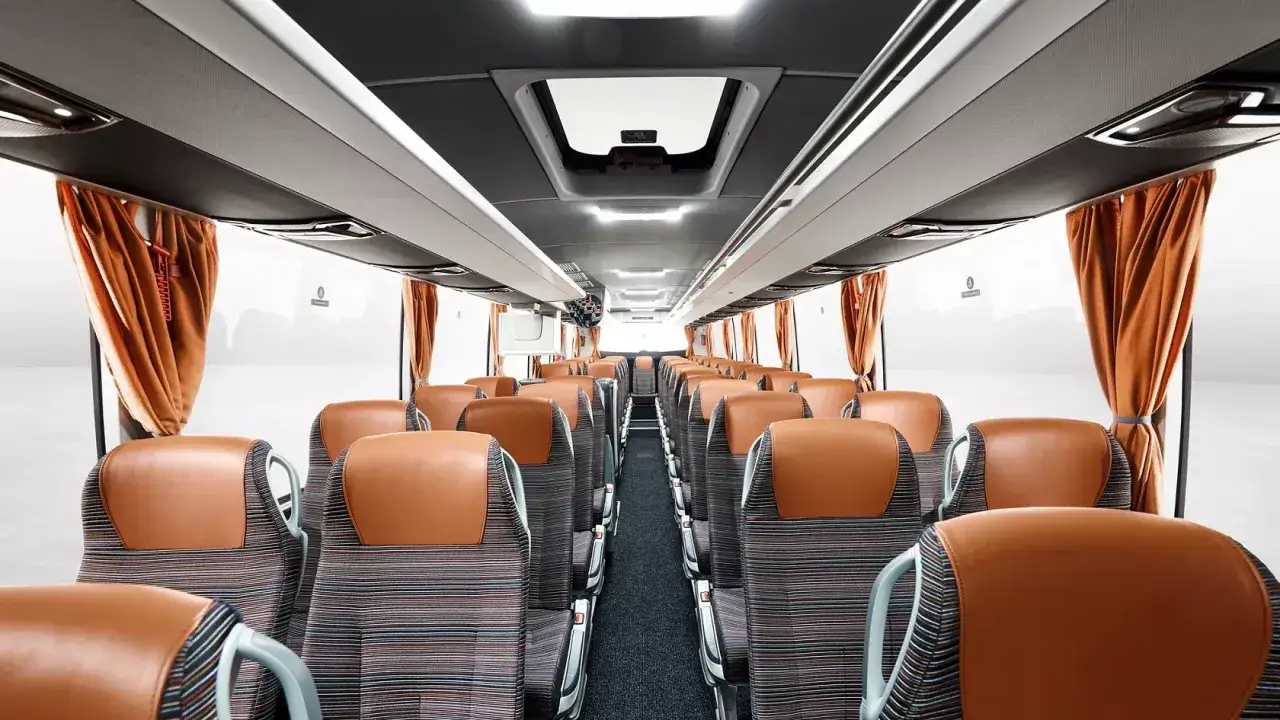 Wnętrze autobusu Yutong z wygodnymi, brązowo-pasiastymi siedzeniami i pomarańczowymi zasłonami.
