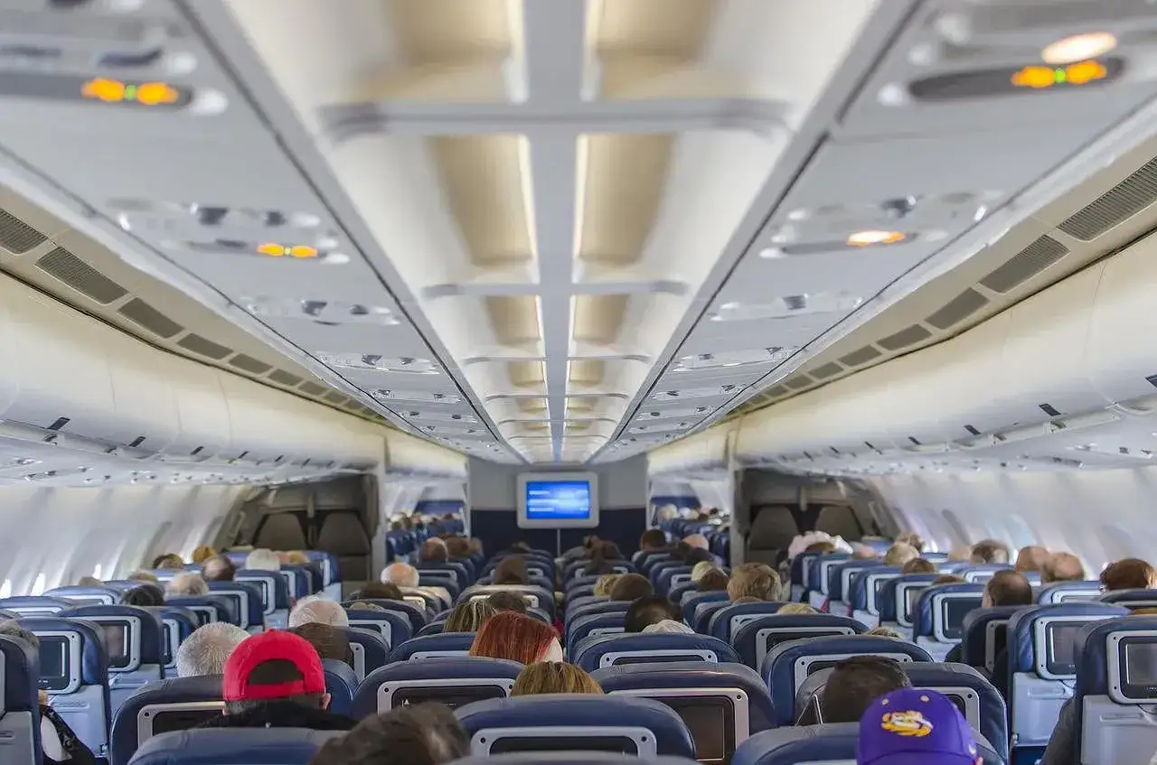 Wnętrze samolotu Ryanair, pełne pasażerów siedzących w rzędach. Widok z tyłu, w kierunku kokpitu.