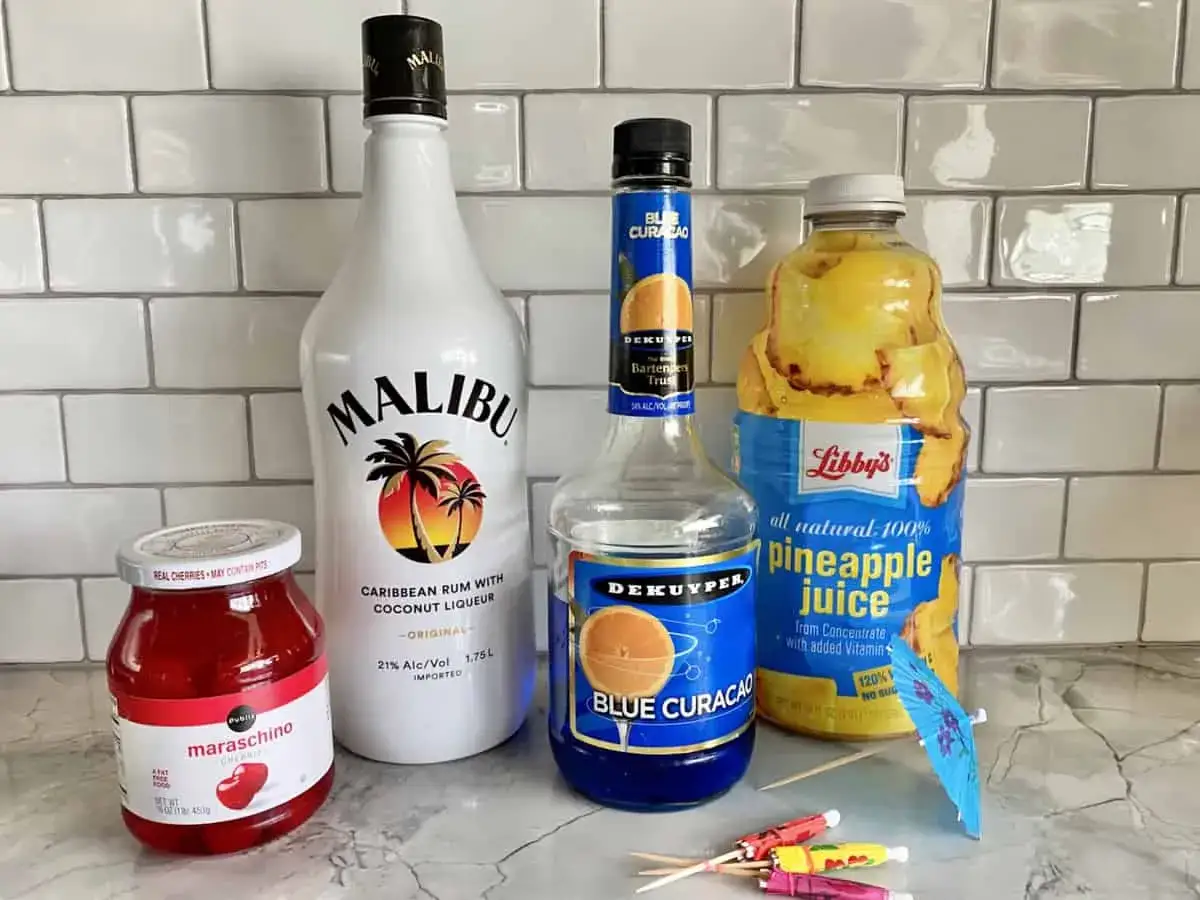 Składniki na drinki z Malibu i Blue Curacao: rum kokosowy, likier Blue Curacao, sok ananasowy, wiśnie maraschino i parasolki.