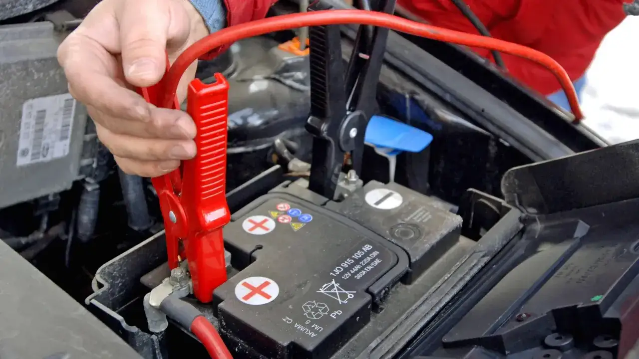 Hand klemmt Starthilfe-Kabel an Autobatterie. Die korrekte Starthilfe Reihenfolge ist entscheidend f&uuml;r die Sicherheit.