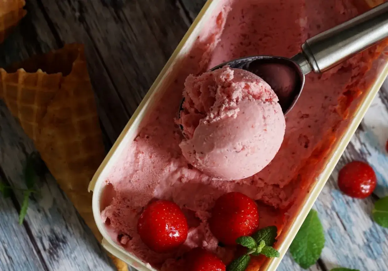 Jak zrobić lody truskawkowe? Pyszne, domowe lody z truskawek, gotowe do podania w wafelku.
