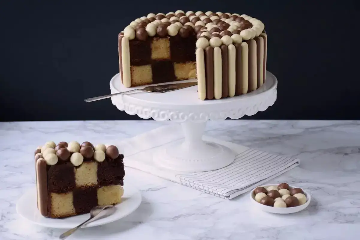 Un d&eacute;licieux g&acirc;teau damier, d&eacute;cor&eacute; de b&acirc;tonnets et de billes chocolat&eacute;es, attend d'&ecirc;tre d&eacute;gust&eacute;. Une part est d&eacute;j&agrave; servie.