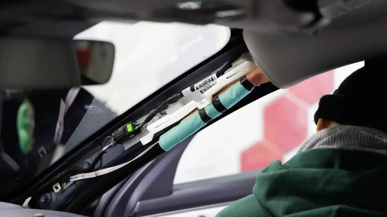 Ein Techniker r&uuml;stet eine Dashcam nach, indem er Kabel im Dachhimmel verlegt.