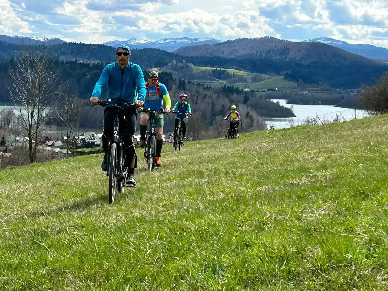 Grupa rowerzystów przemierza malownicze trasy rowerowe Podkarpacia, podziwiając jezioro i góry.