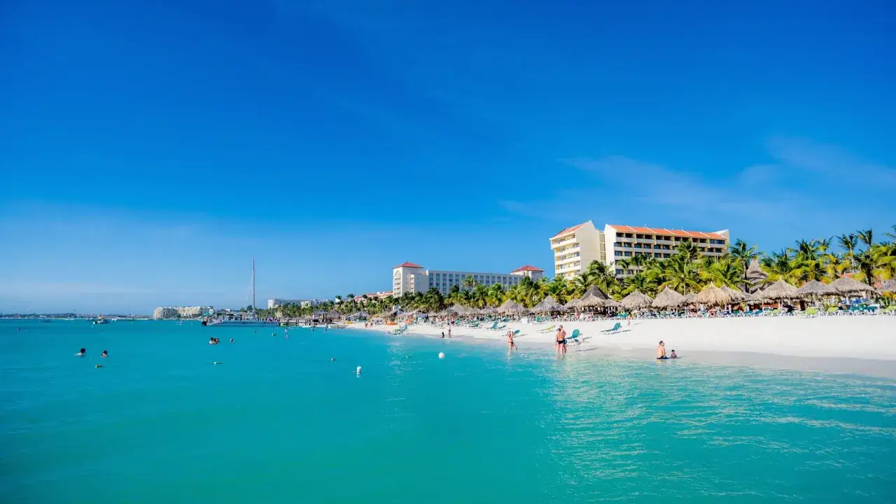 Traumhafter Strand auf Aruba mit türkisfarbenem Wasser und Palmen. Perfekt für die **Aruba beste Reisezeit**!