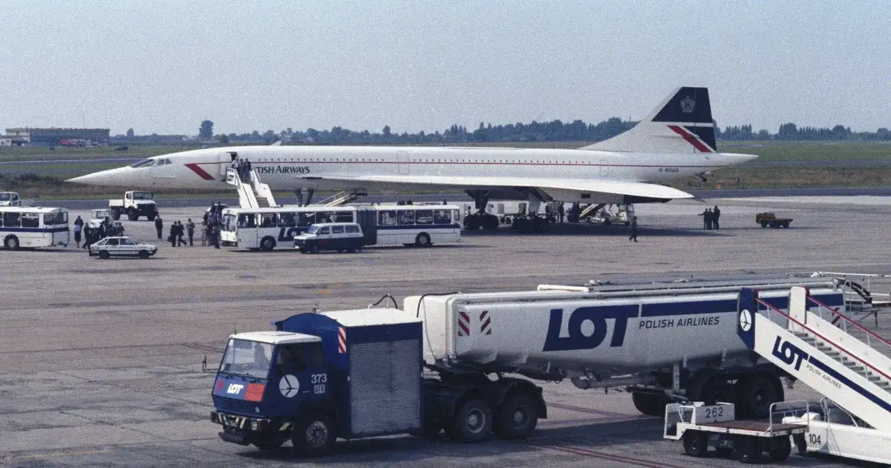 Samolot Concorde British Airways na płycie lotniska. Obok autobusy i cysterna LOT. Lot Concorde trwał krótko.