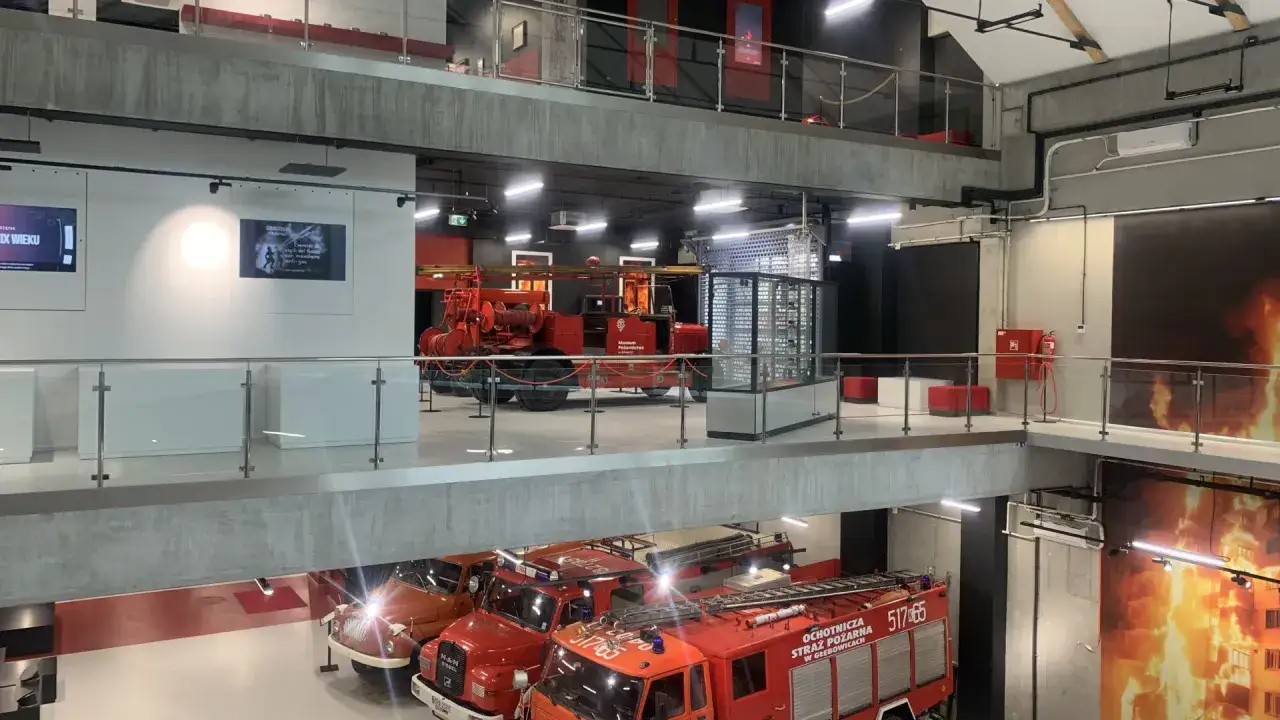 Wnętrze muzeum pożarnictwa w Alwerni. Widać zabytkowe wozy strażackie i ekspozycje.