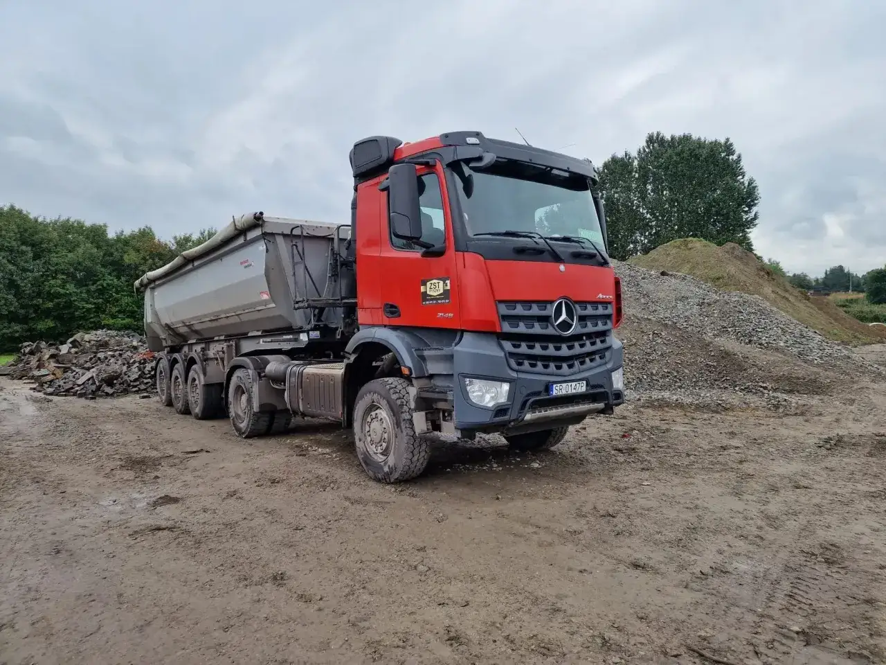 Ciężarówka z naczepą na budowie, gotowa do transportu materiałów. Taki pojazd może przewieźć znaczną część maksymalnej ładowności tira w Polsce.
