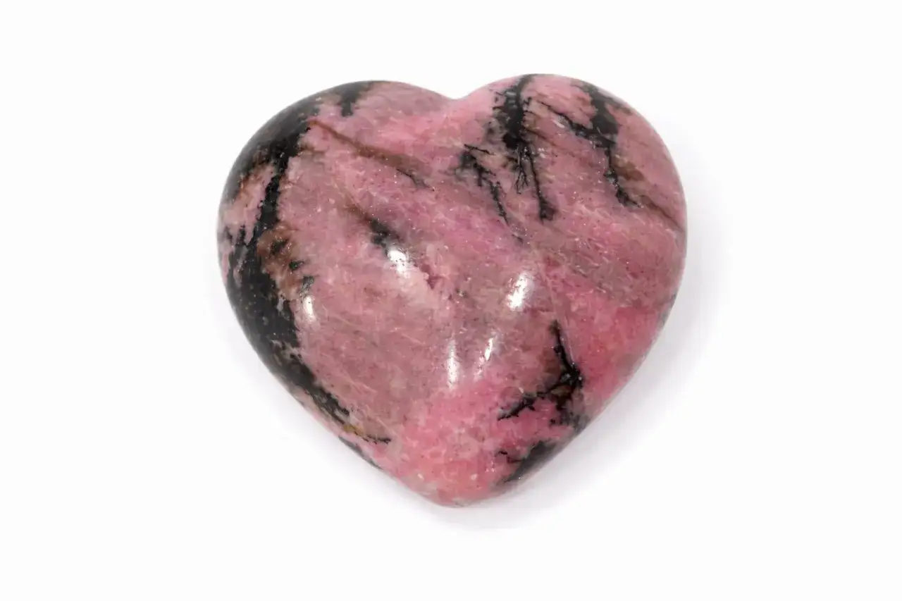 Herzförmiger Trommelstein in Rosa mit schwarzen Einschlüssen. Seine Wirkung soll beruhigend und harmonisierend sein.