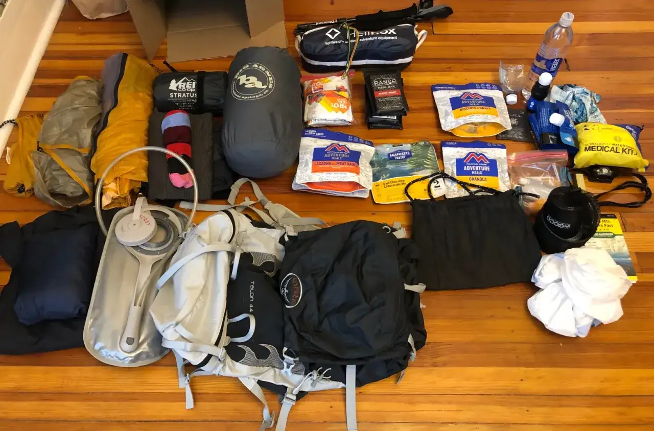 Ausr&uuml;stung f&uuml;r Trekking: Zelt, Schlafsack, Rucksack, Wasserflasche, Trekkingnahrung und Erste-Hilfe-Set liegen bereit.