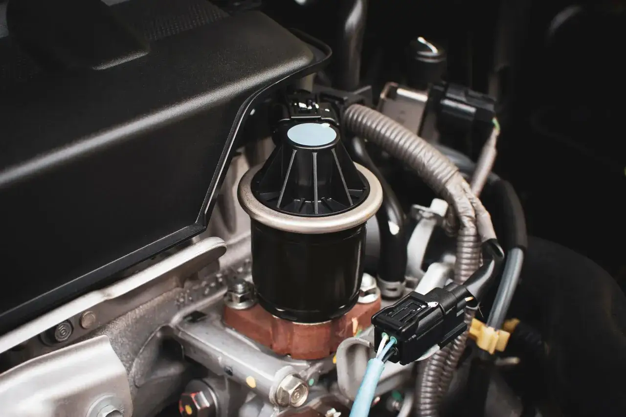Close-up of a new EGR valve replacement part installed in a car engine, ready for a smooth drive.