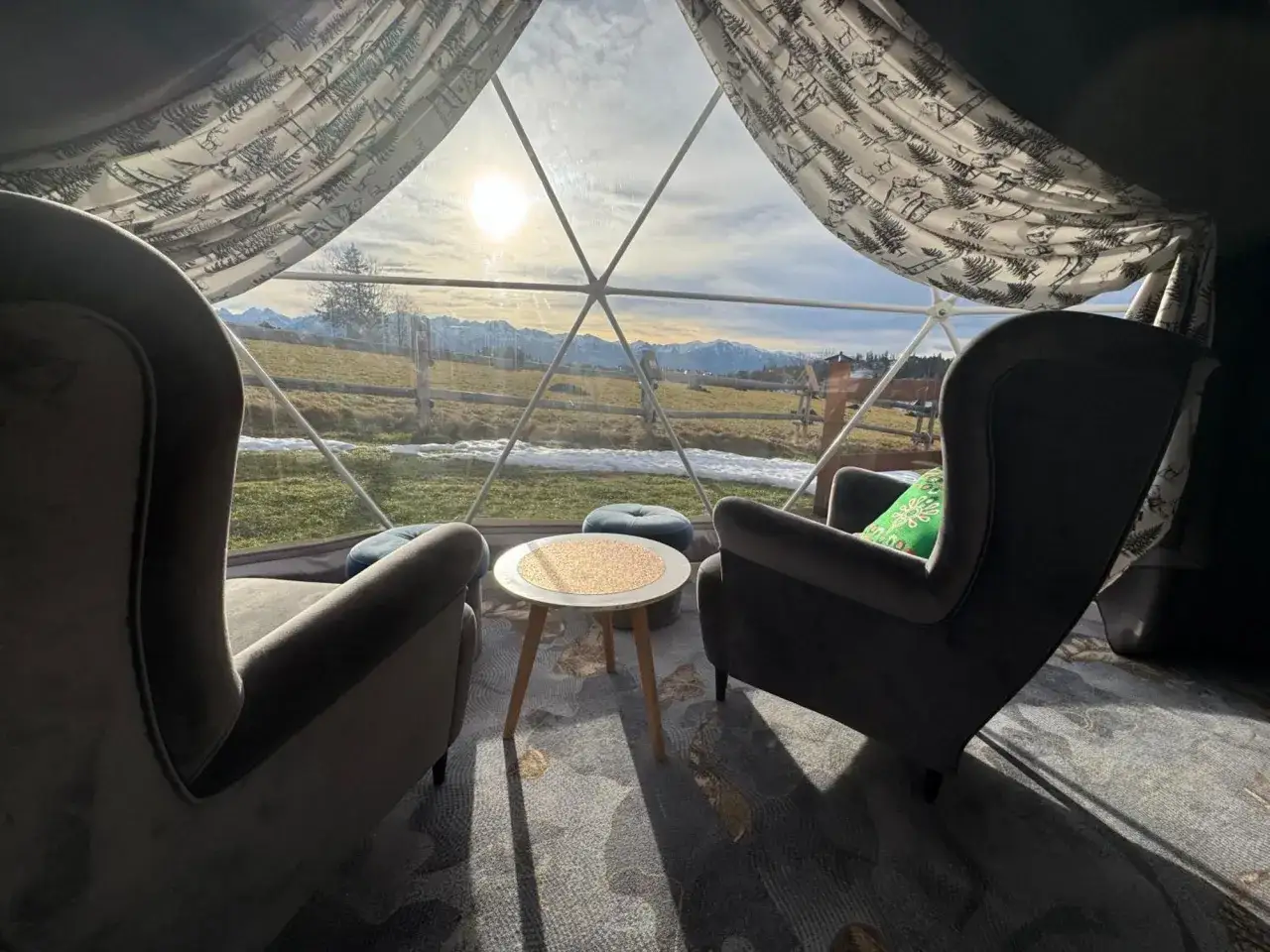 Przytulne fotele i stolik w namiocie sferycznym. Widok na g&oacute;ry i słońce. Idealne miejsce na glamping w Wielkopolsce.