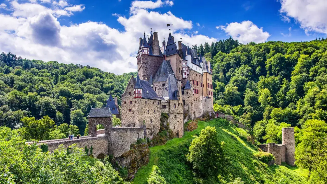 M&auml;rchenschloss Eltz, ein Juwel unter den **Reiseziele Ostdeutschland**, thront auf einem H&uuml;gel, umgeben von sattgr&uuml;nen W&auml;ldern.