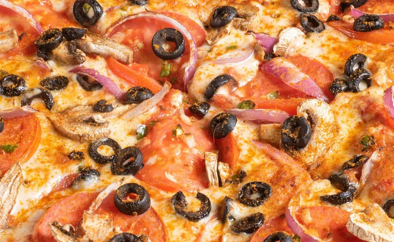 Pyszna pizza z pomidorami, oliwkami, pieczarkami i czerwoną cebulą. Te dodatki do pizzy tworzą idealne połączenie smak&oacute;w.