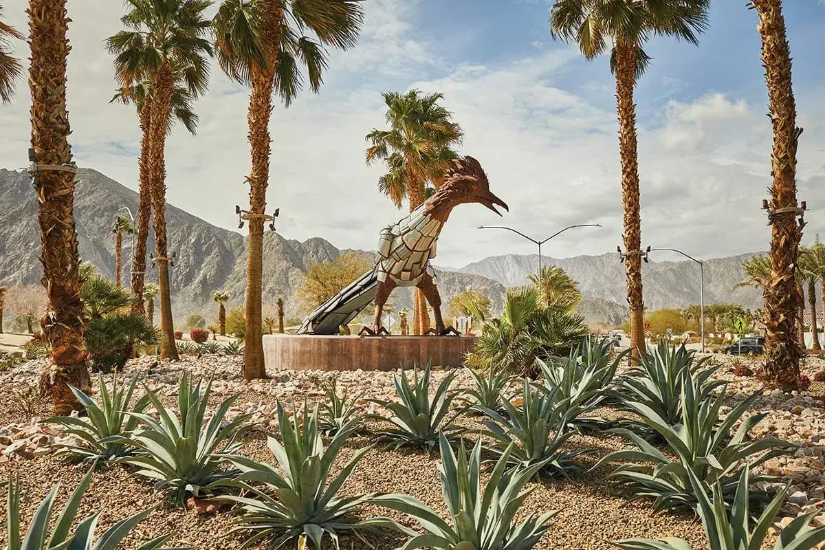 Scultura di roadrunner nel deserto, un'icona che ricorda cos'è il Coachella: musica, arte e paesaggi mozzafiato sotto palme e montagne.