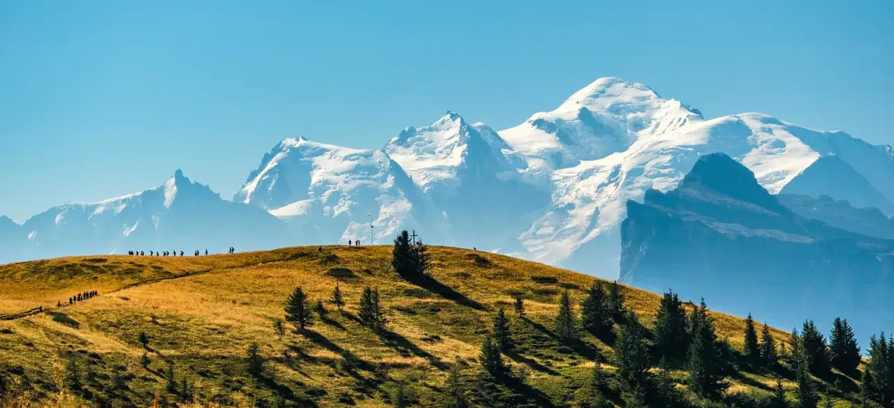 Widok na majestatyczny Mont Blanc, gdzie jest mont blanc, z trawiastego wzgórza z grupą turystów.