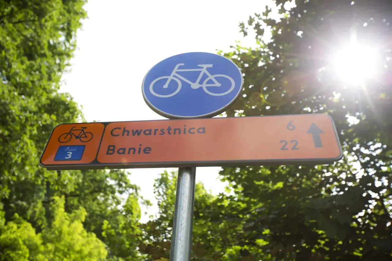 Znak rowerowy z niebieskim symbolem roweru i pomarańczową tablicą kierunkową do Chwarstnicy i Baniewic. Idealny na wycieczkę **blue velo**.