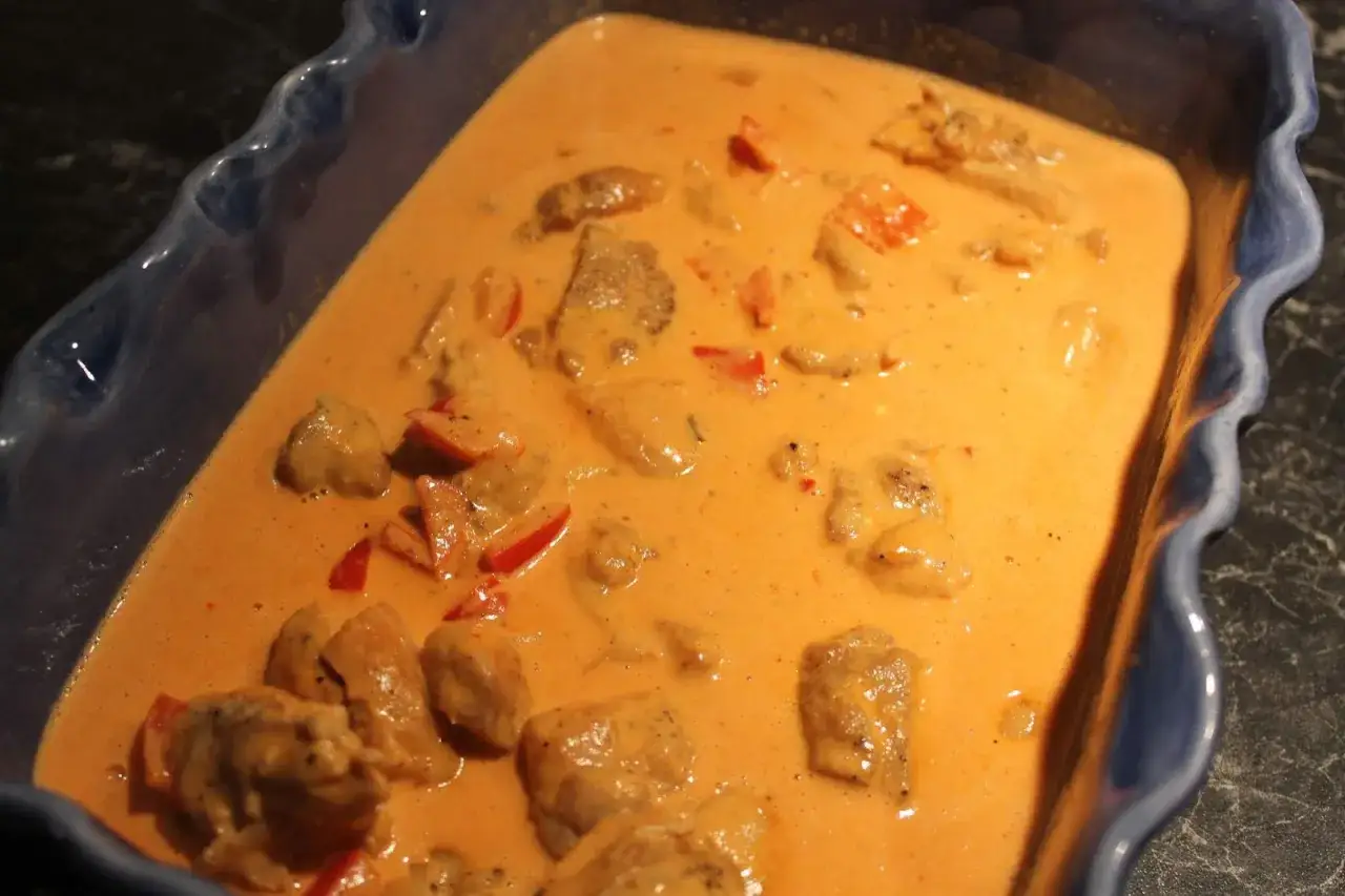 En krämig kycklinggryta med paprika i en blå ugnsform. Doftar ljuvligt och ser ut att vara perfekt till middagen.