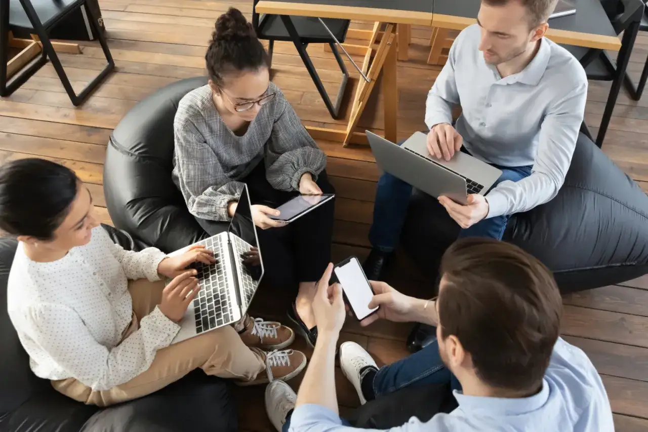 Ett team av fyra personer, inklusive en social media specialist, diskuterar idéer kring bärbara datorer och surfplattor.