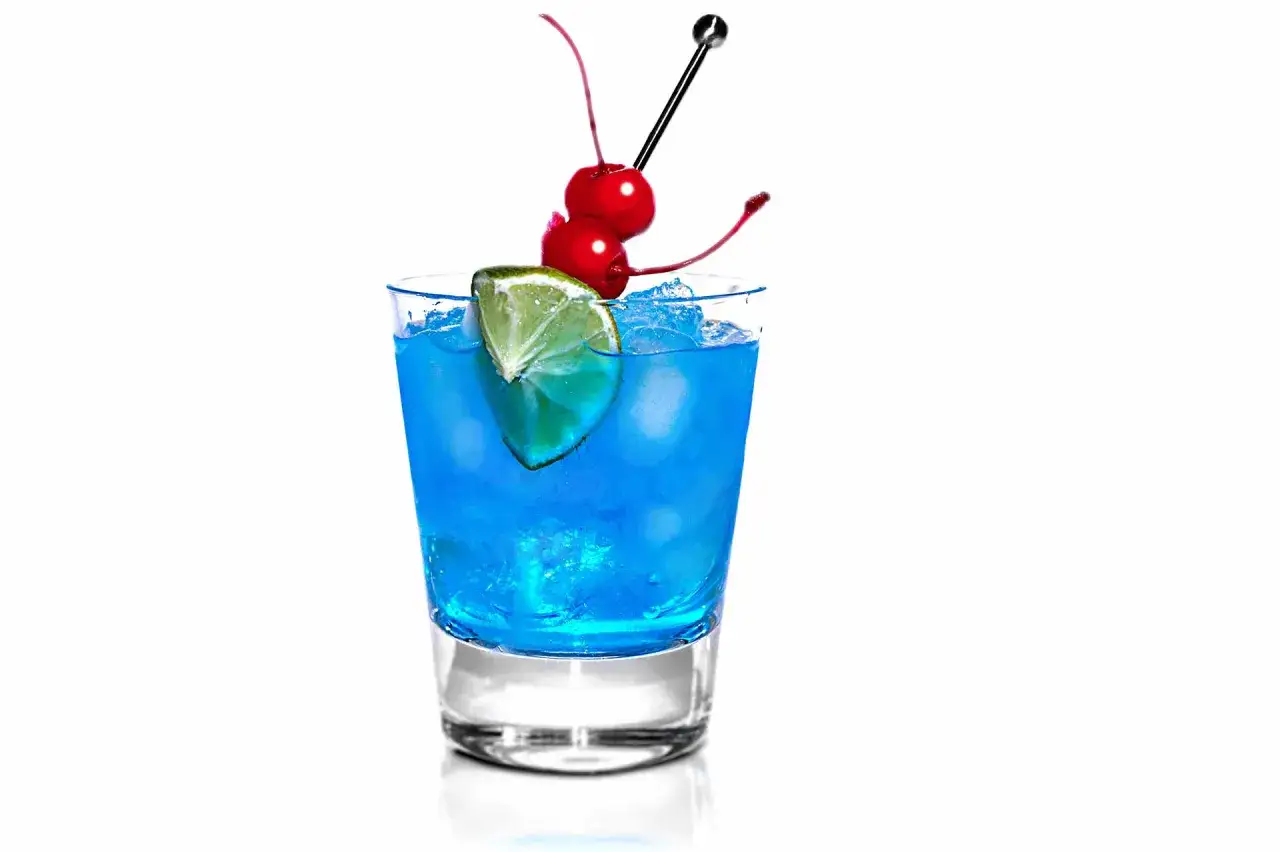 Erfrischender blue curacao cocktail mit Eis, Limettenspalte und Kirschen auf einem Spie&szlig;.