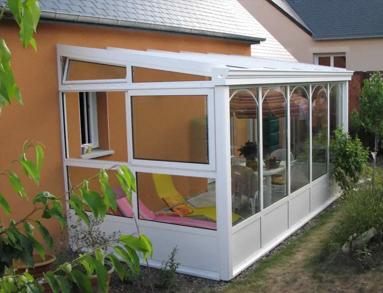 V&eacute;randa d&eacute;montable sans permis de construire, avec chaises longues et table &agrave; manger. Id&eacute;ale pour profiter du jardin.