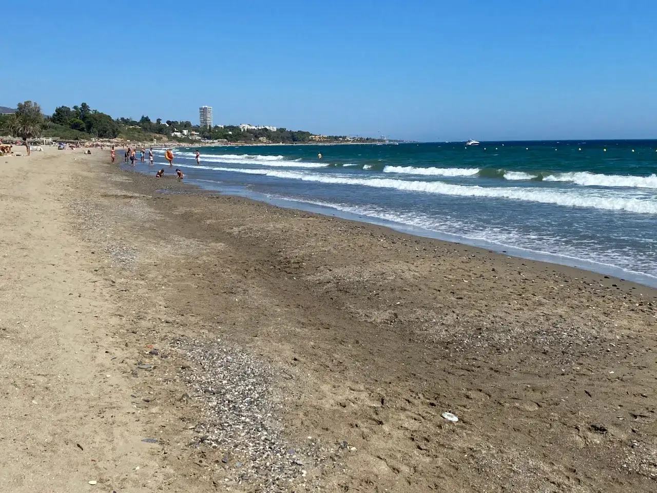 Sonniger Tag am playa del cable. Menschen genie&szlig;en das Meer, Wellen brechen am Strand.