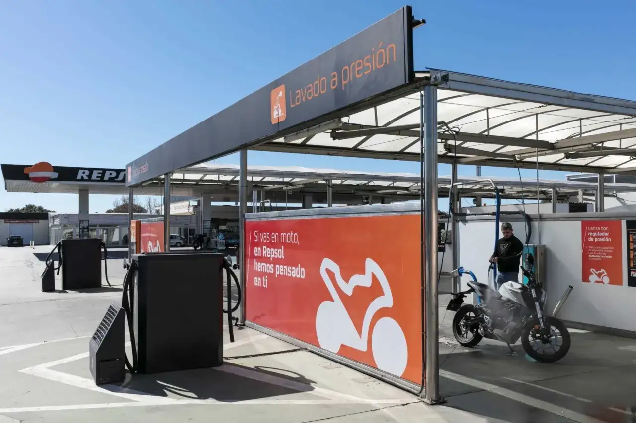 Hombre lavando su moto a presión en una gasolinera Repsol. El servicio de lavado está pensado para motoristas.
