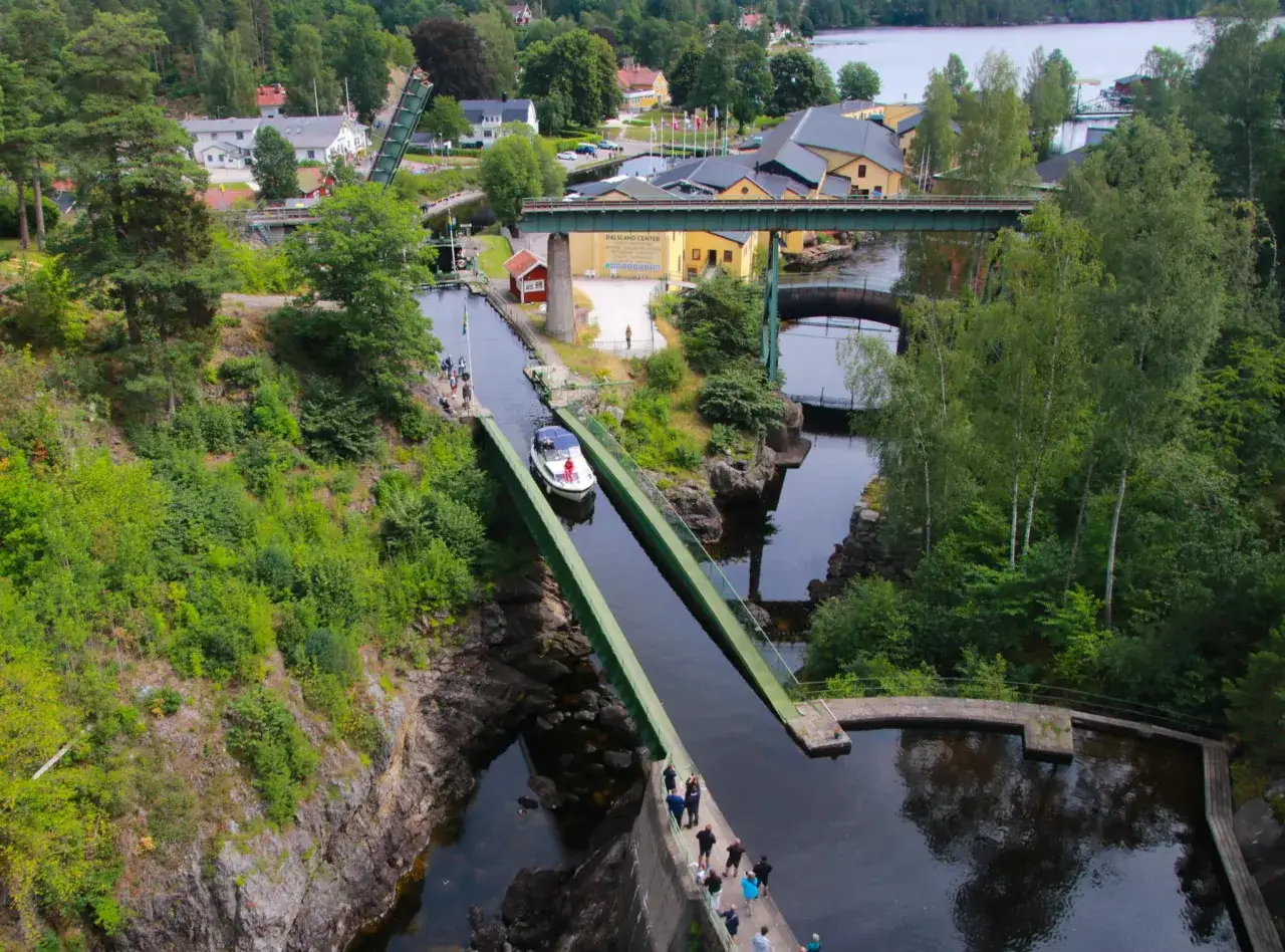 En båt färdas genom akvedukten i Håverud, en imponerande konstruktion med broar och slussar omgiven av grönskande natur.