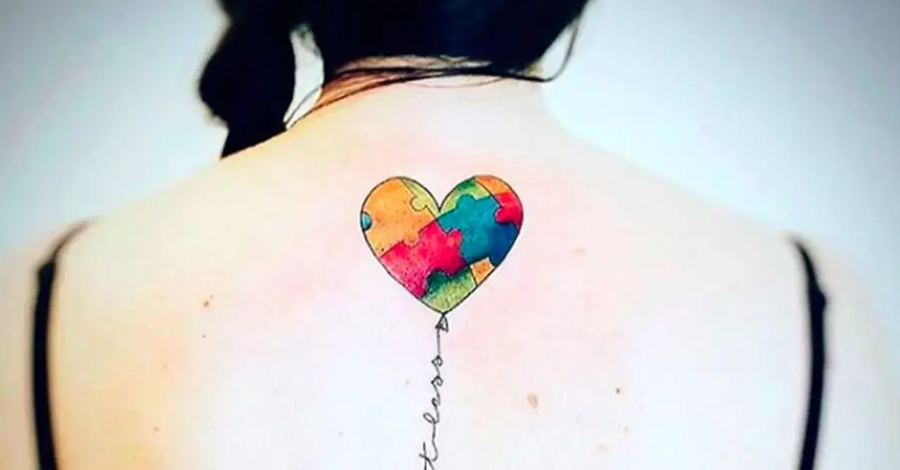 Kolorowe serce z puzzli, symbol autyzmu, tatuaż na plecach.