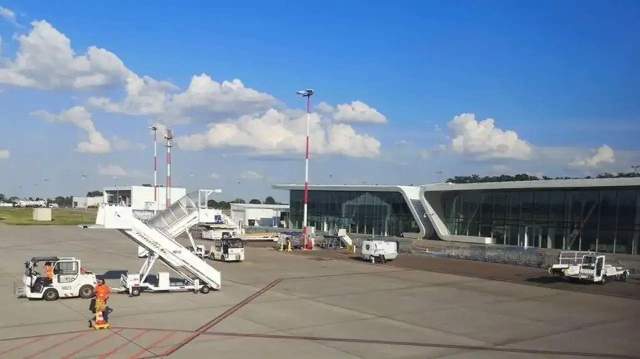Lotnisko Świdnik przyloty: nowoczesny terminal, schody lotnicze i pojazdy obsługi naziemnej na płycie lotniska w słoneczny dzień.