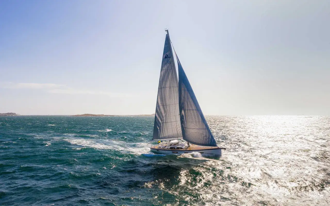 Eine Hallberg-Rassy 69 gleitet mit vollen Segeln &uuml;ber das glitzernde Meer.