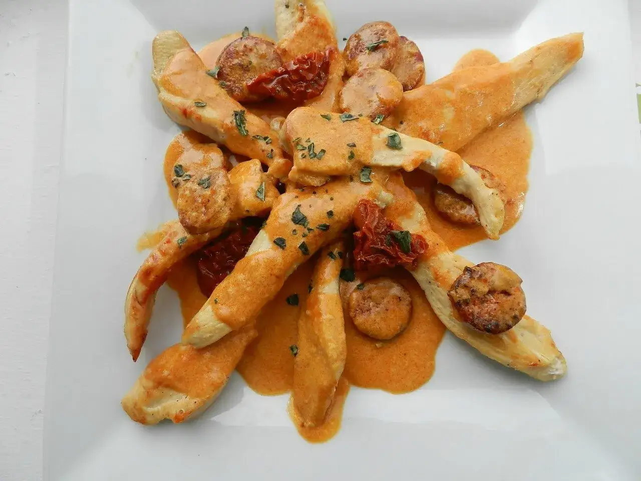 Aiguillettes de poulet enrobées d'une sauce crémeuse orangée, parsemées de rondelles de chorizo et de tomates séchées. Une recette savoureuse !