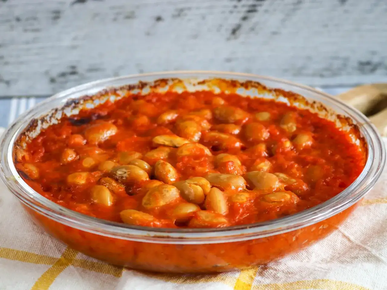 Herzhaftes Fasolakia Rezept in Tomatensauce, in einer Glasschüssel serviert.