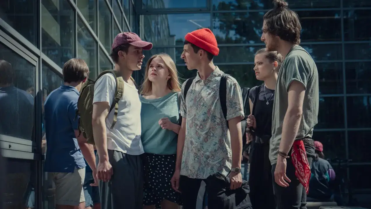 Grupa nastolatków dyskutuje przed budynkiem. Czy to scena z seriali Netflix dla nastolatków?