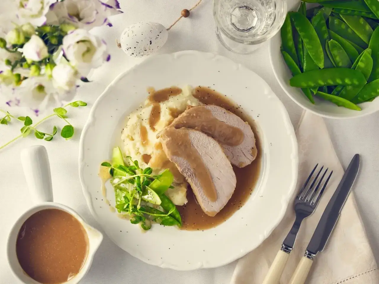 Szynka pieczona na obiad w sosie, podana z puree ziemniaczanym i zielonym groszkiem. Idealny posiłek na rodzinne spotkanie.