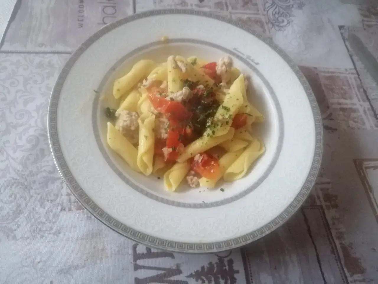 Un piatto di garganelli alla contadina con pomodoro e carne macinata, guarnito con prezzemolo fresco.