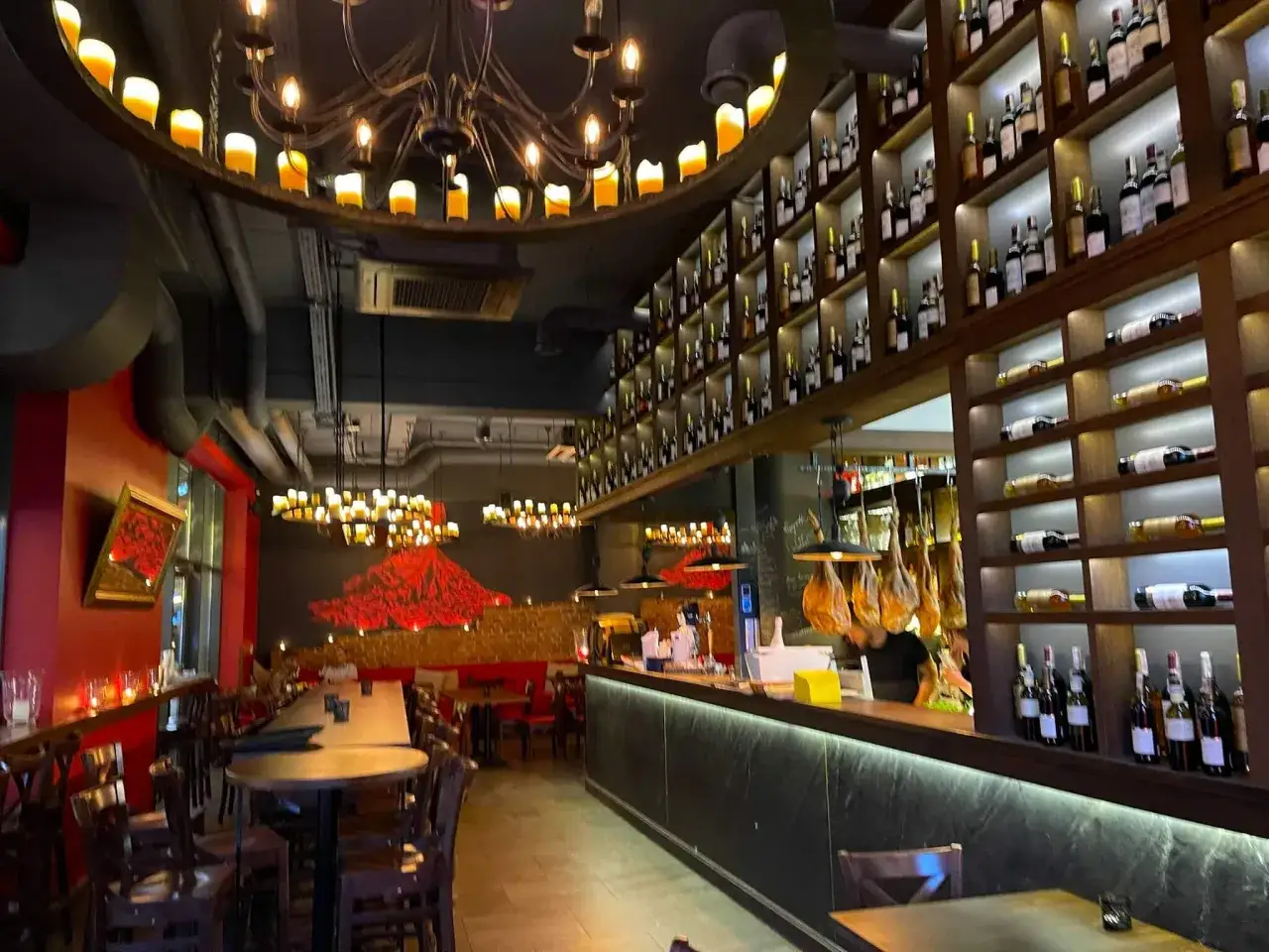Przytulne wnętrze restauracji w Gdańsku na Starym Mieście, z bogato zaopatrzonymi półkami win i klimatycznym oświetleniem.