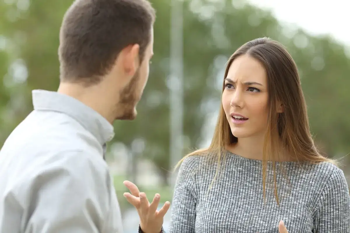 Mujer con expresi&oacute;n de duda y enfado habla con un hombre. &iquest;C&oacute;mo ayudar a una persona celosa y desconfiada?